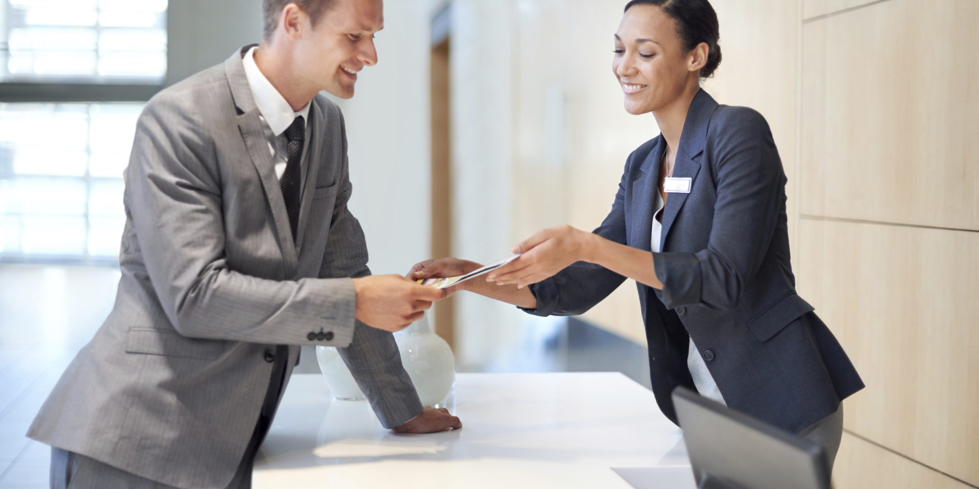 A handsome young man handing over a credit card to a woman